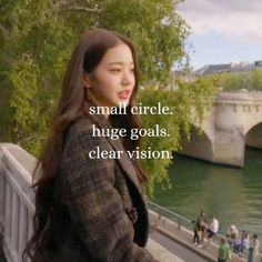 a woman standing next to a river with a bridge in the background that says small circle, huge goals clear vision