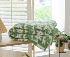 two green towels sitting on top of a wooden shelf next to a lamp and window