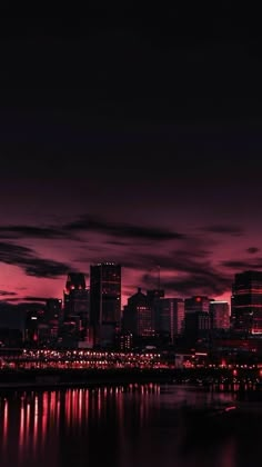 the city skyline is lit up at night with lights reflecting in the water and clouds