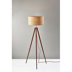 a wooden tripod floor lamp with a beige shade