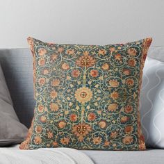 a decorative pillow on a couch with pillows and throw pillows in the background, including an orange flowered design