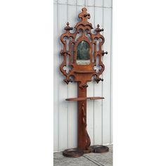 an ornate wooden mirror on display in front of a white wall