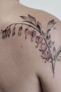 the back of a woman's shoulder with flowers and leaves tattooed on her left side