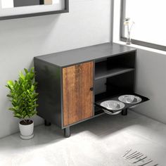 a black cabinet with two bowls on it next to a potted plant