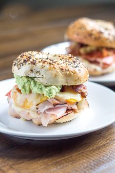 two sandwiches with meat, cheese and guacamole are on white plates next to each other