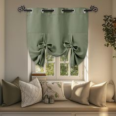 a window with green curtains and pillows on it