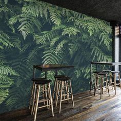 an image of a restaurant setting with green leaves on the wall and bar stools