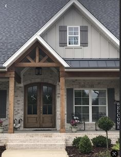 a house with gray shingles and white trim on the front door is shown in this image