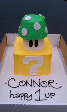 a cake in the shape of a box with a mario mushroom on top that says, connor happy 1 up