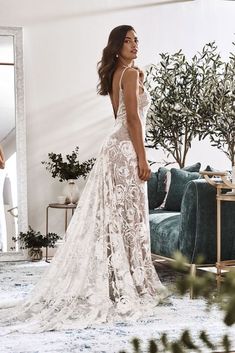 a woman standing in front of a mirror wearing a wedding dress with an open back