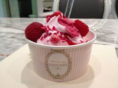 a cup filled with ice cream and raspberries