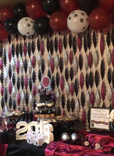 a table topped with lots of desserts and balloons in front of a party wall