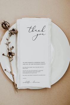 a white plate topped with a piece of paper next to a dried plant and a thank you card