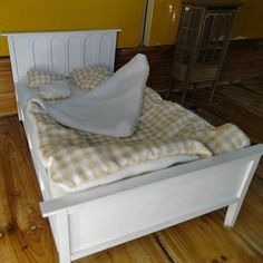 a bed that has some pillows on it in a room with wood floors and yellow walls