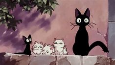 black cat with four white kittens sitting in front of a tree and rock wall