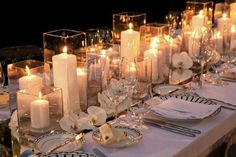 the table is set with candles, plates and silverware for an elegant dinner party