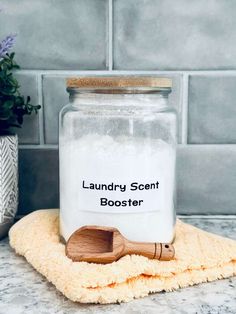 a wooden spoon sitting on top of a towel next to a jar filled with laundry scent