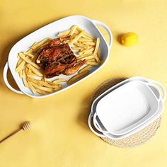 two plates with food in them on a yellow surface next to a bowl and fork