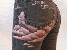 the back of a woman's jeans with clouds painted on it and words that read look up