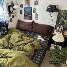 a bed with green sheets and pillows in a room filled with pictures on the wall