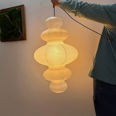 a person is holding a string attached to a light fixture in the shape of lanterns