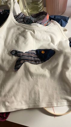 a white shirt with a fish design on the front and back, sitting on a table