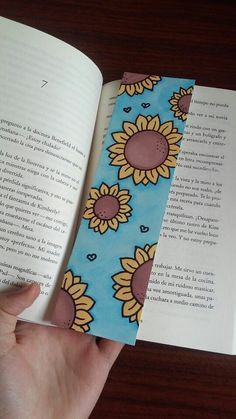 a bookmark with sunflowers on it is held in front of an open book