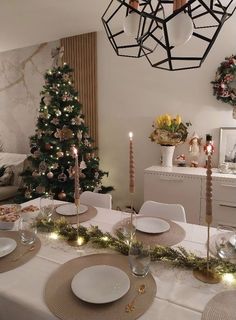 a dining room table set for christmas dinner with candles and decorations on the table top