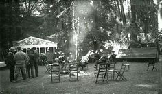 black and white photograph of people sitting around a campfire