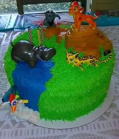 the cake is decorated with animals and grass