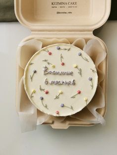 a cake in a box with writing on the side and flowers around it that says baummau ombreaue