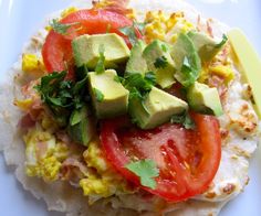 an omelet with tomatoes, avocado and other toppings on it