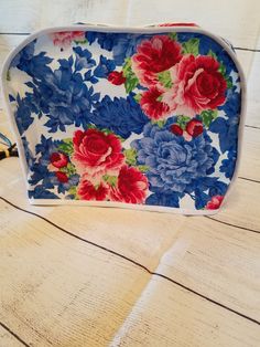 a blue and red flowered purse sitting on top of a wooden table