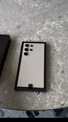 a black and white box sitting on top of a table next to a cell phone