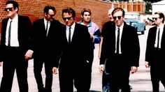 a group of men in suits and ties walking down the street with one man wearing sunglasses