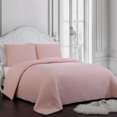 a bed with pink sheets and pillows in a room