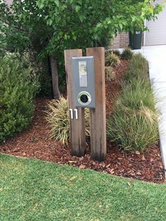 an outdoor toilet in the middle of some grass and bushes next to a building with a sign on it