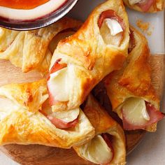 ham and cheese pastries on a cutting board with dipping sauce