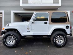 a white jeep parked in front of a garage