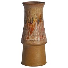 a brown vase is sitting on a white surface and it looks like it has been dipped with paint