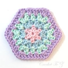 a crocheted hexagon is shown in pastel colors and sits on a white surface