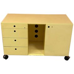 a yellow cabinet with four drawers and three black knobs on the bottom half is open