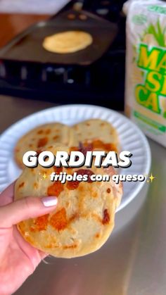 a person holding up a piece of food on a paper plate that says gorditass fritos con queso