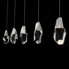 five crystal pendants hanging from strings on a black background