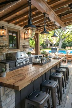 an outdoor kitchen with bar stools and grill