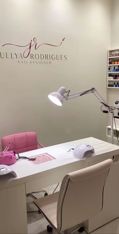 a white desk with a pink chair in front of it and a logo on the wall behind it