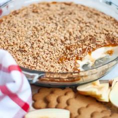 an apple pie with graham crackers on the side and apples in the bowl next to it