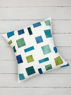 a white pillow with green and blue squares on it