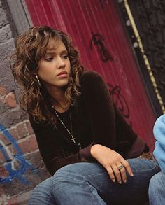 a woman sitting on the ground next to a man in jeans and a black shirt