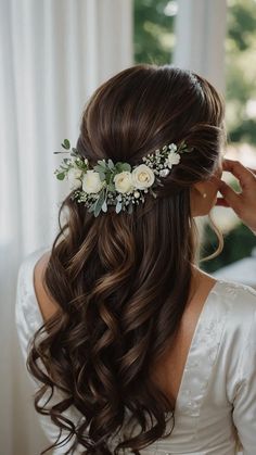 a woman with long hair and flowers in her hair is looking into the distance while wearing a white dress